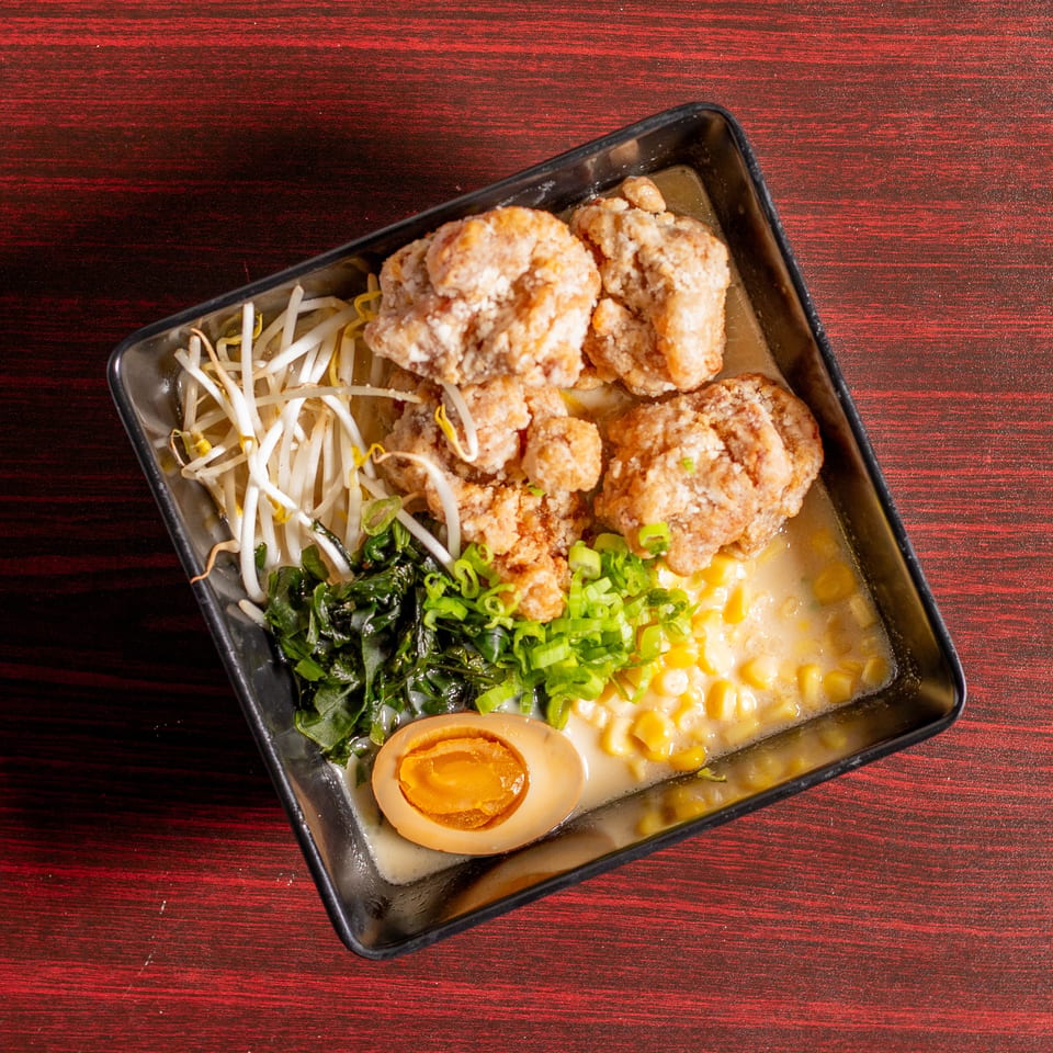 Ramen bowl with fried chicken, bean sprouts, seaweed, corn, green onions, and a soft-boiled egg.
